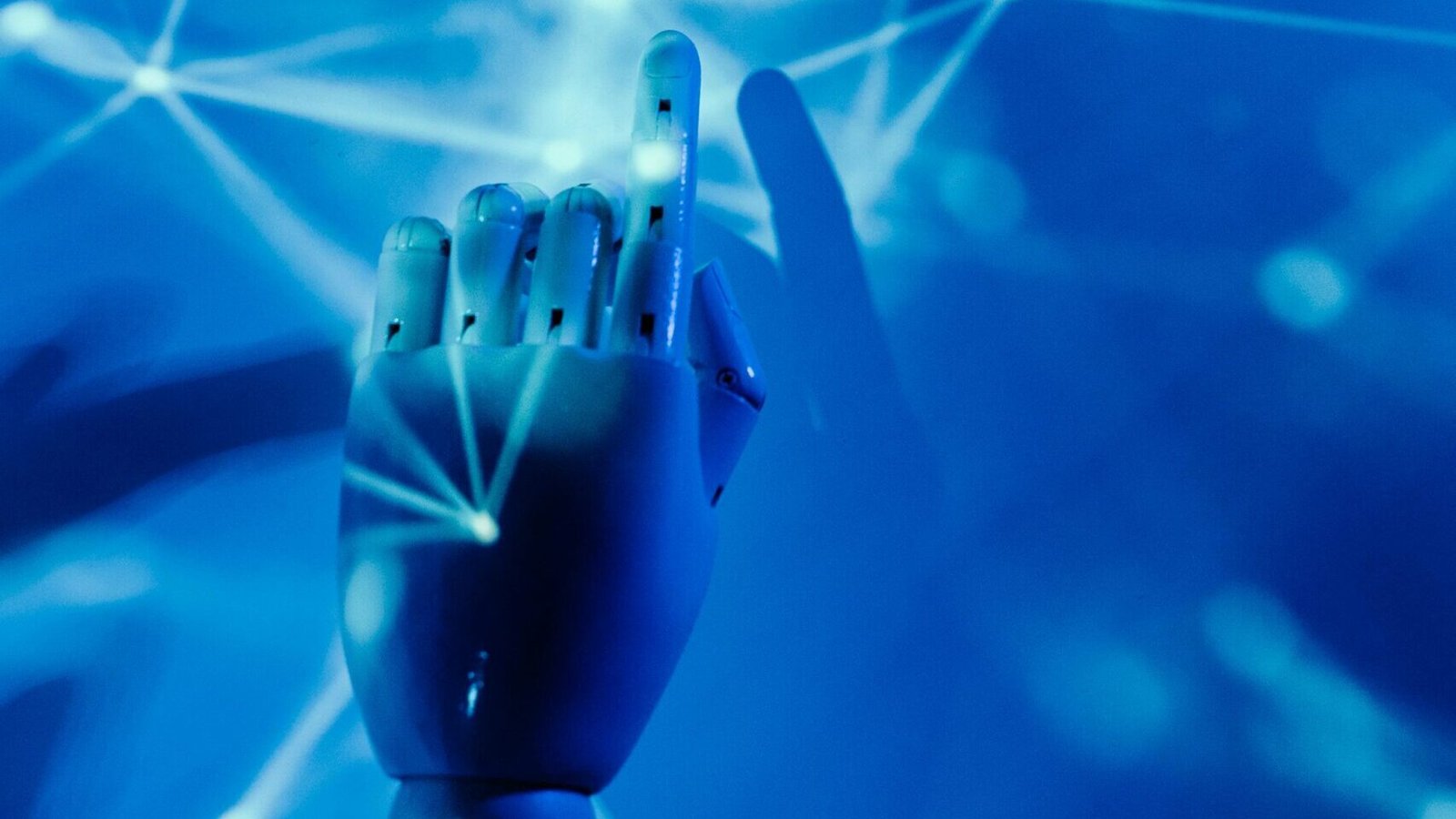 Futuristic robotic hand touching a digital network on a blue background.
